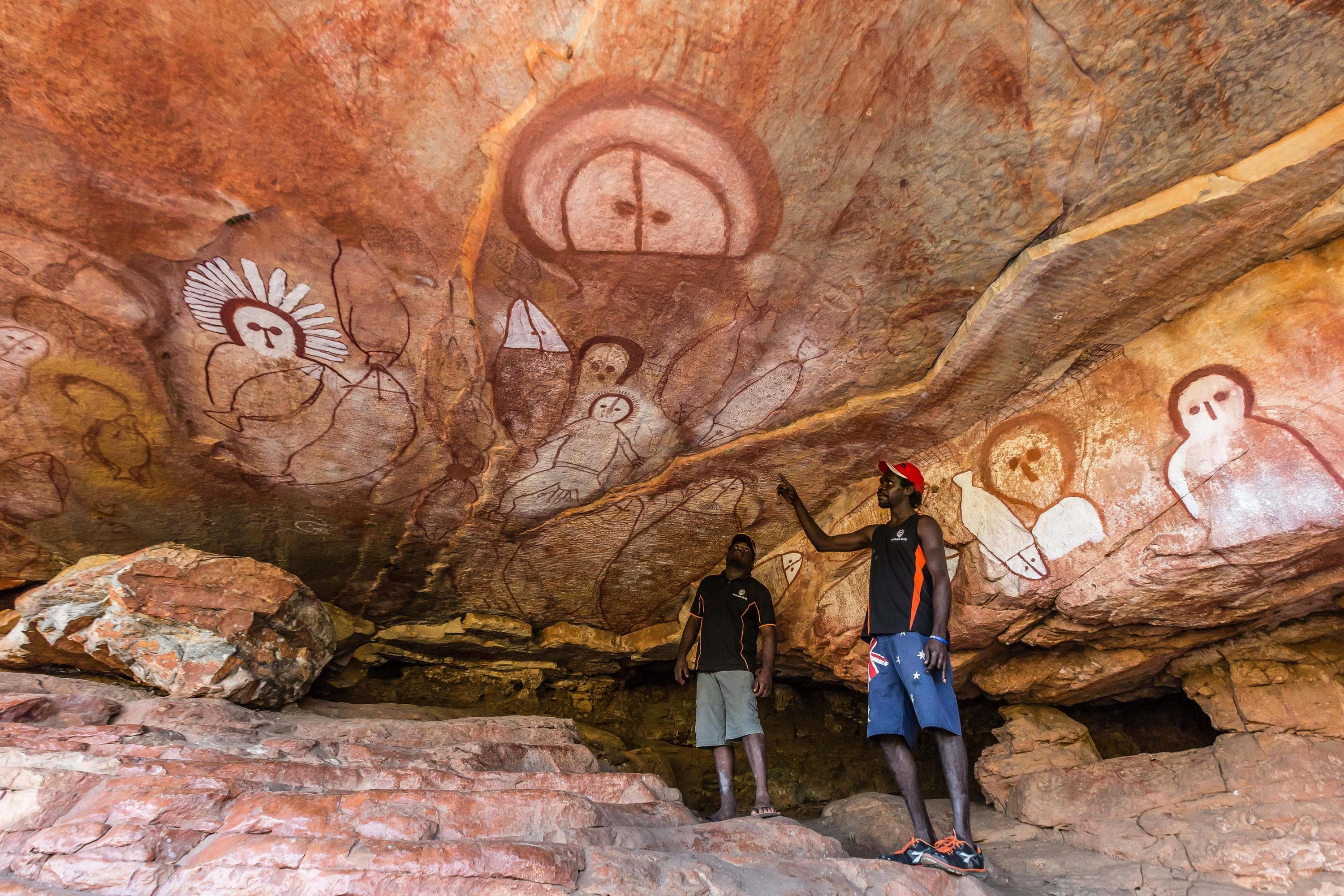 Aboriginal guides presenting Wandjina cave artwork in sandstone caves at Raft Point, Kimberley, Western Australia, Australia