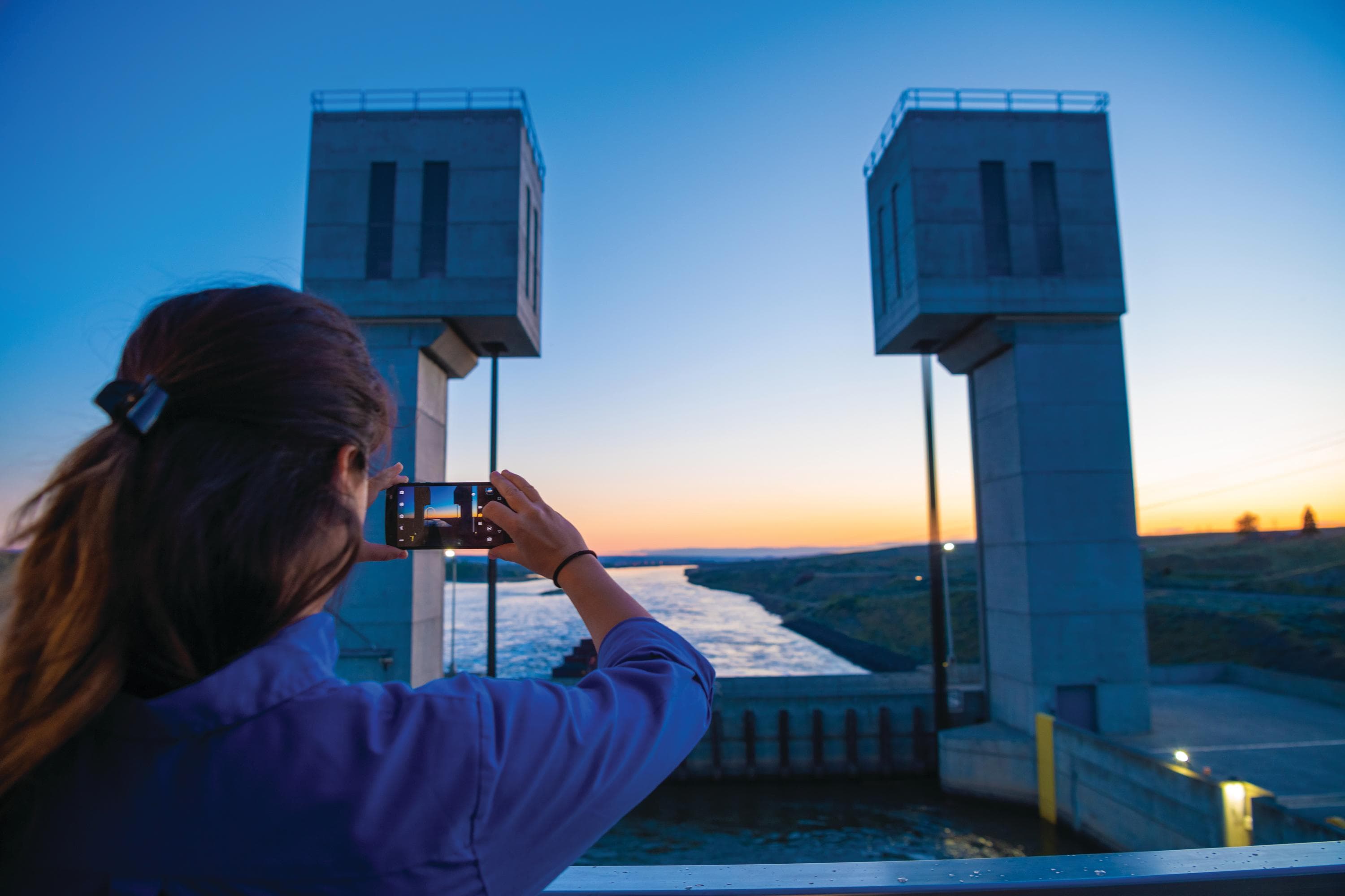 A guest taking photos passing through the Ice Harbor Lock and Dam on the Columbia River from the ship National Geographic Quest, Franklin, Washington