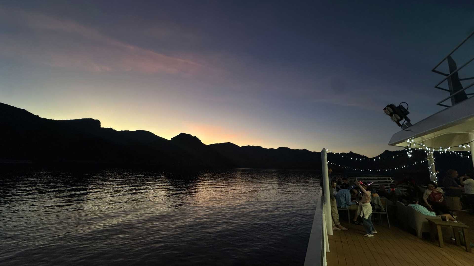 guests watch sunset from the deck of a ship